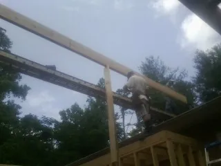 Carpenter setting a ridge beam over a new addition frame — Ice Dam Removal by Roofing Brothers in Pelahatchie