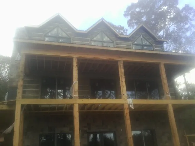 Dormers and porch framing on a large log home under construction — Roof Coating work by our crew in Pelahatchie