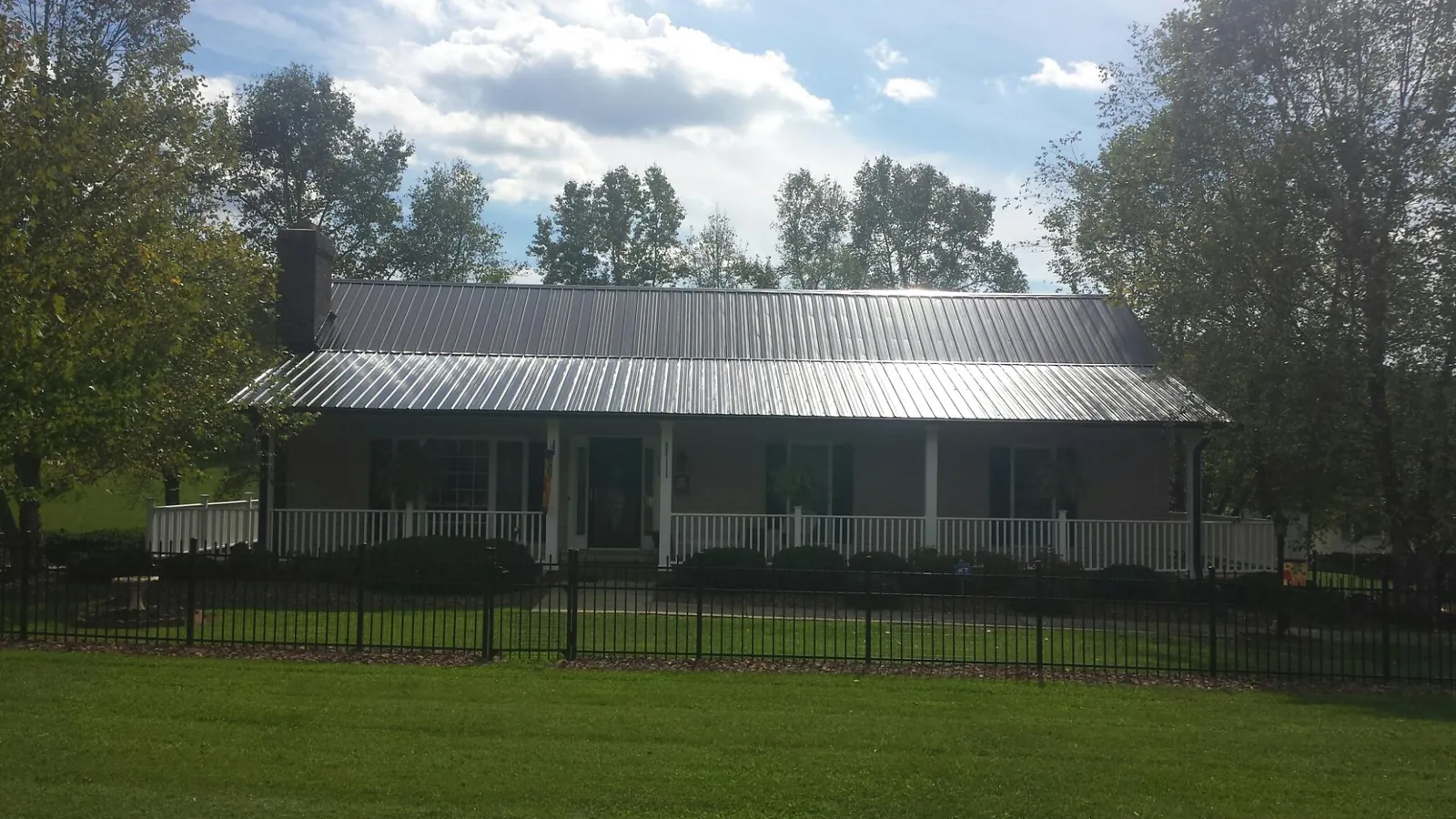 Gray metal roof on a brick ranch with a full width front porch — Gutter Guard Installation work by our crew in Pelahatchie